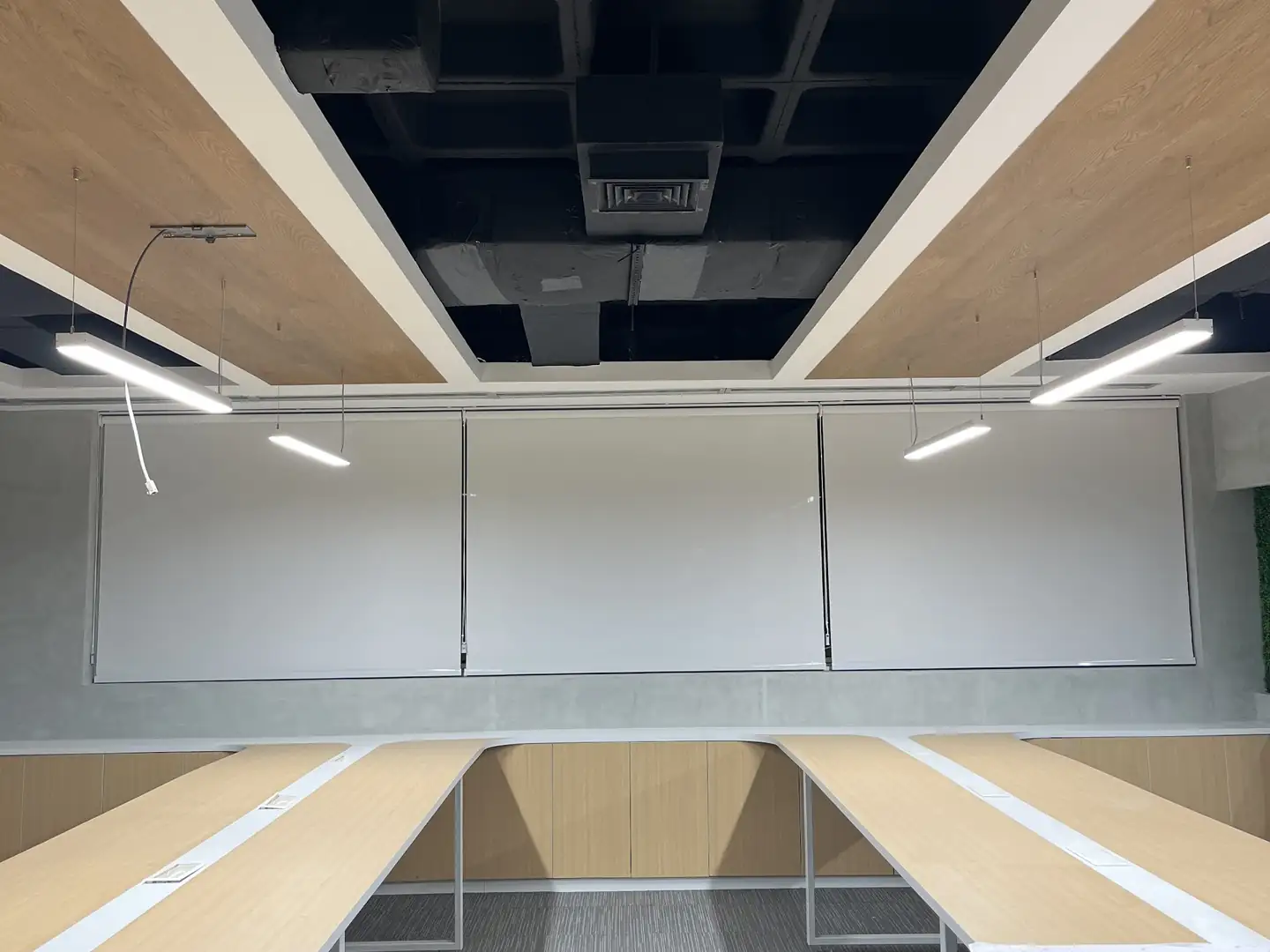 Persianas para escritórios e empresas: três telas solares em rolô, lado a lado, na parede do fundo de um escritório