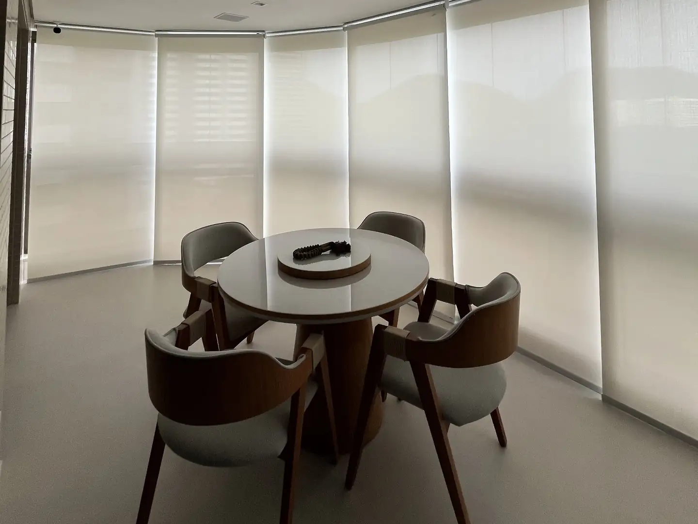 Cortinas e persianas motorizadas: telas solares motorizadas em uma varanda envidraçada com mesa e cadeiras